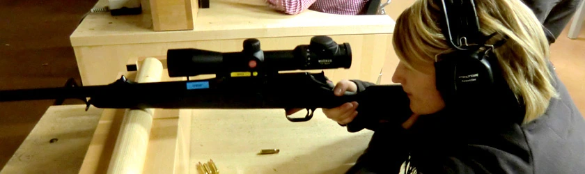 Frau mit Gehörschutz schießt am Stand mit einer Repetierbüchse