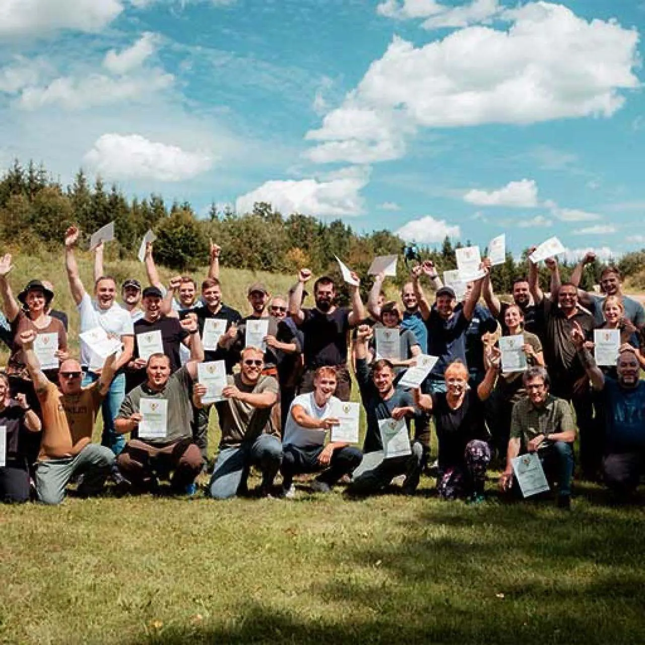 Gruppenfoto: Absolventinnen und Absolventen der Jagdschule Abt halten ihre Zeugnisse hoch