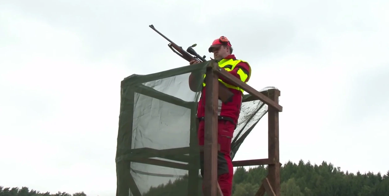 Schütze in roter Schutzkleidung auf einem Drückjagdbock