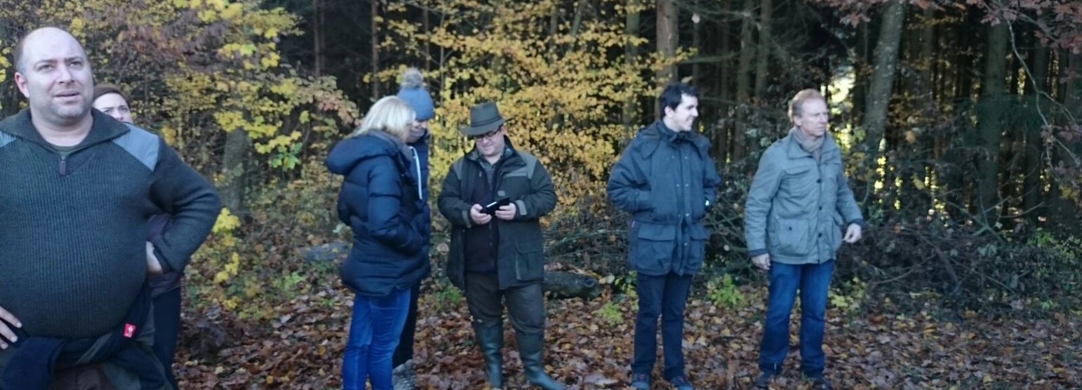 Ausbilder erklärt einer Kursgruppe im herbstlichen Wald etwas