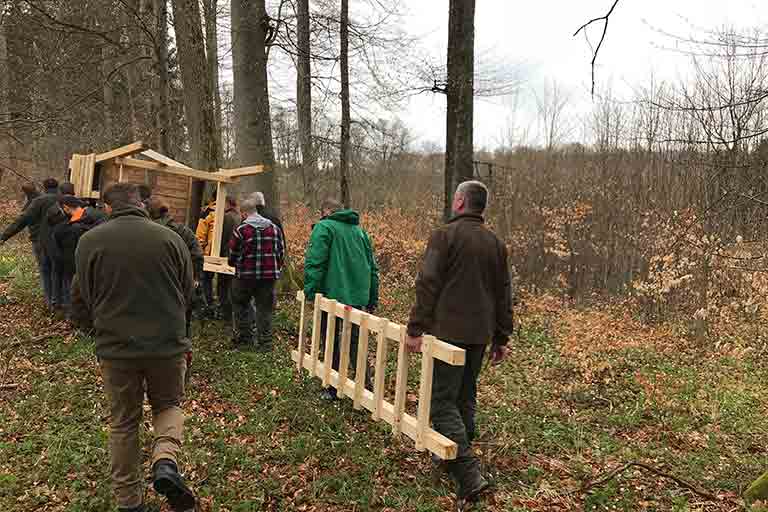 Teilnehmer bauen im Lehrrevier gemeinsam eine Kanzel auf